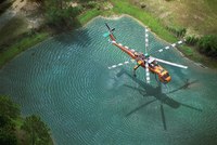 Looking down on a helicopter dipping into a pond during fires in Florida